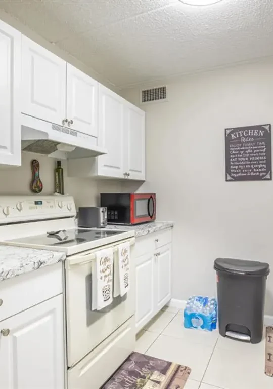 a kitchen with white cabinets and a microwave at The  Element At 464