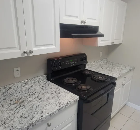 a kitchen with white cabinets and black stove at The  Element At 464